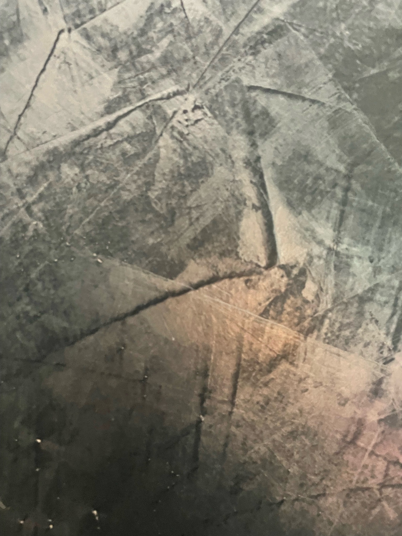 Szara, teksturowana powierzchnia z widocznymi pęknięciami i przetarciami, przypominająca tynk dekoracyjny lub efekt na ścianie.