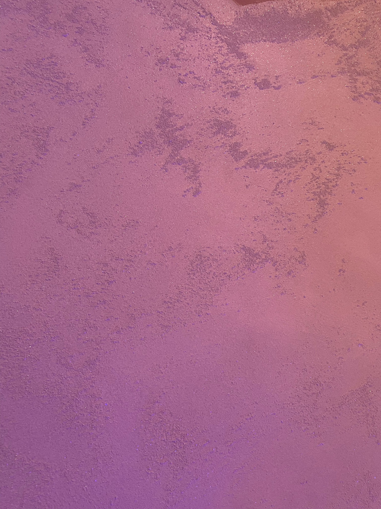 Fioletowa ściana z dekoracyjną fakturą i subtelnym połyskiem, oświetlona od góry, tworząca gradient kolorystyczny.