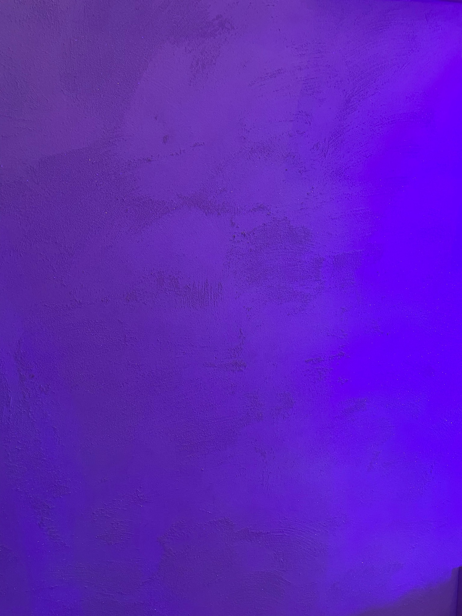 Fioletowa ściana z widoczną fakturą i nierównomiernym oświetleniem, gdzie prawa strona jest jaśniejsza.