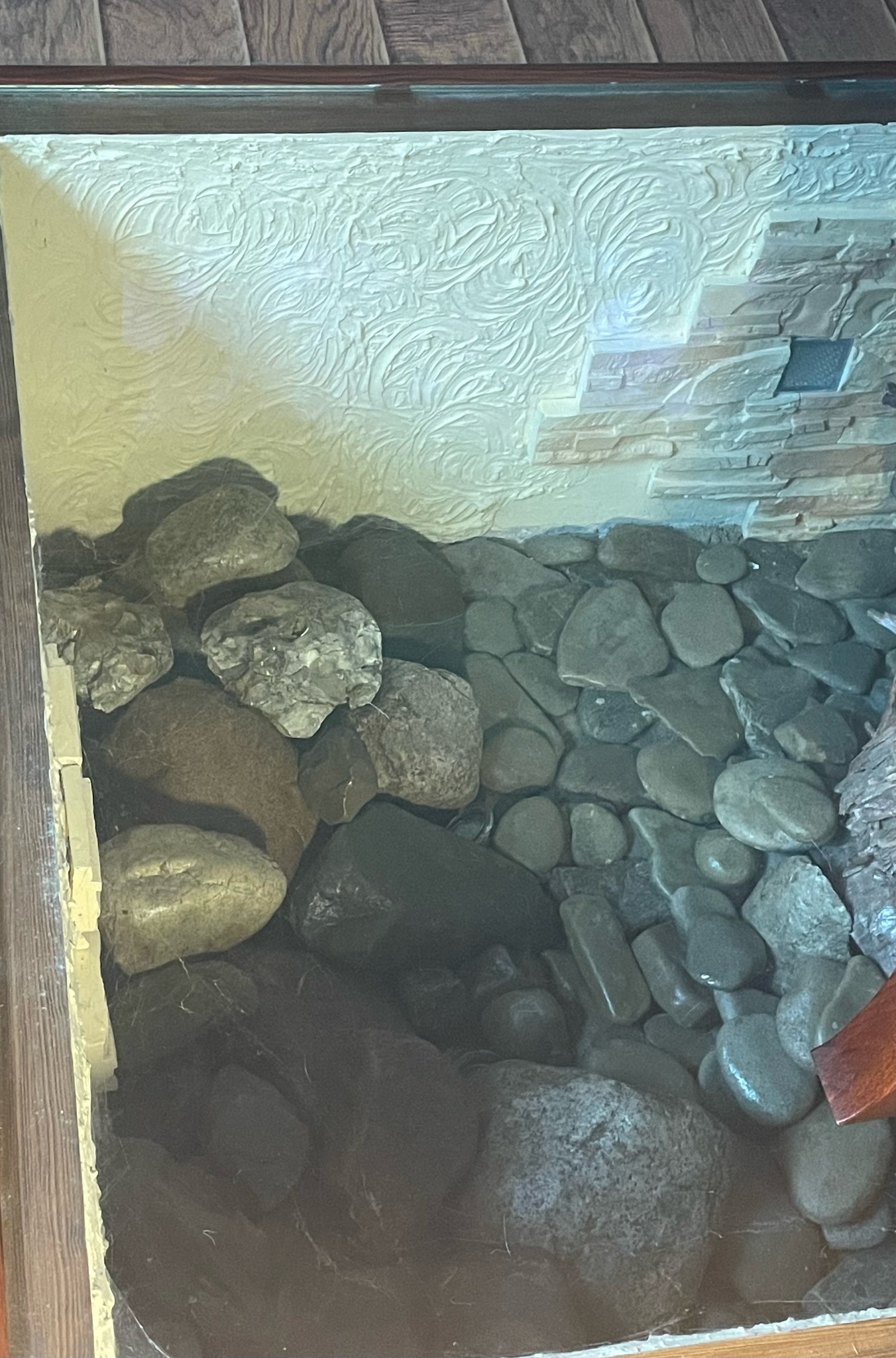 Fragment ściany z dekoracyjną strukturą, przechodzącą w kamienną mozaikę, wypełniony różnej wielkości kamieniami.