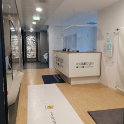 BANAŚ CONSTRUCTION Radosław Banaś - Nowoczesne wnętrze biura radiologicznego z recepcją, drewnianą podłogą i dekoracyjnymi panelami ściennymi w tle.
