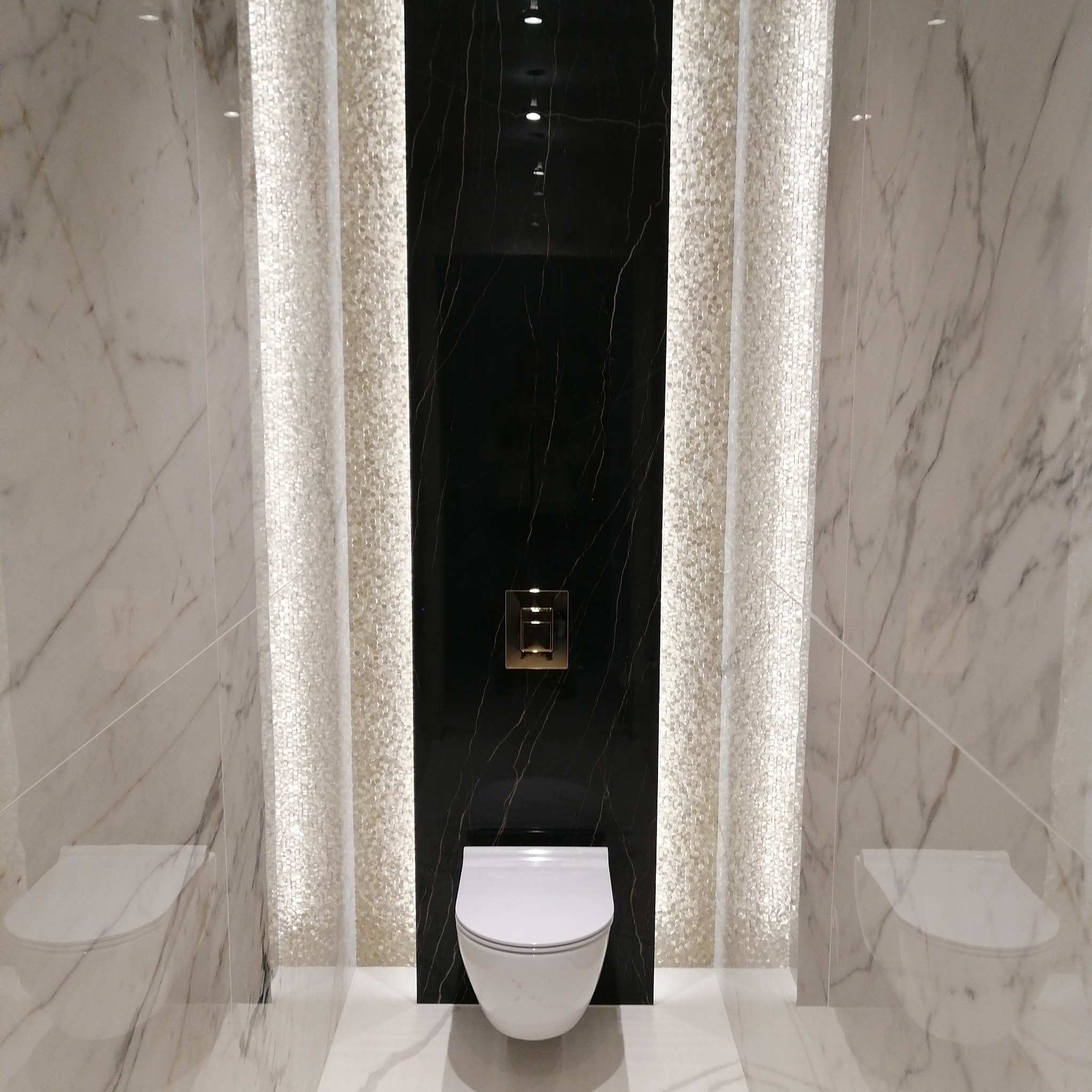 Nowoczesna toaleta podwieszana z czarną ścianą akcentującą i mozaikowymi panelami po bokach, wykończona marmurem w Rzeszowie.