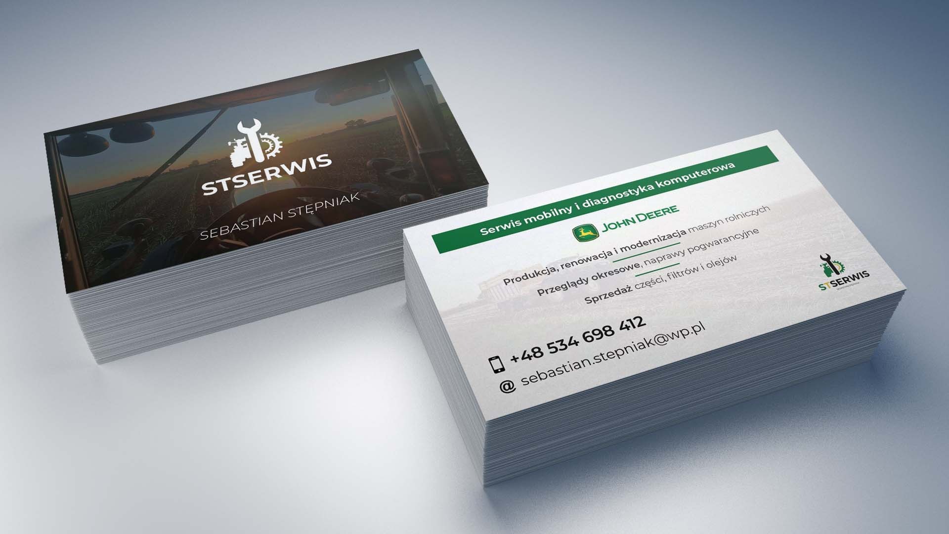 Stosy wizytówek firmy świadczącej usługi serwisu mobilnego i diagnostyki komputerowej maszyn rolniczych John Deere, z logo firmy STSERWIS i danymi kontaktowymi.