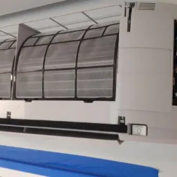 Otwarty panel klimatyzatora ściennego z widocznymi filtrami i wewnętrzną elektroniką, dolna krawędź maskowana niebieską taśmą malarską.