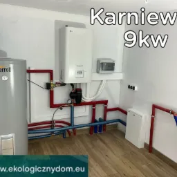 Instalacja grzewcza z szarym zbiornikiem Ferroli, białym piecem LG Therma V i widocznymi rurami w kolorach czerwonym i niebieskim, zamontowana w pomieszczeniu z panelami podłogowymi.