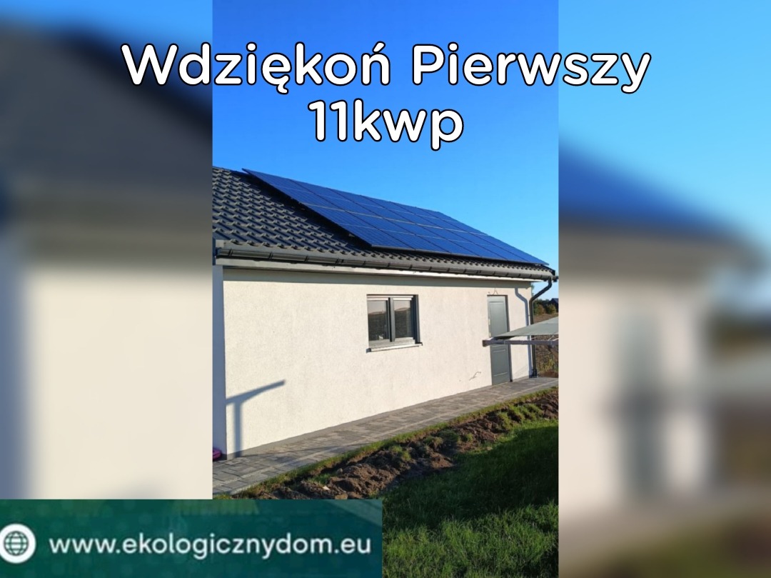 Dom jednorodzinny z grafitowymi panelami słonecznymi na ciemnoszarym dachu, widok z poziomu trawnika w słoneczny dzień.