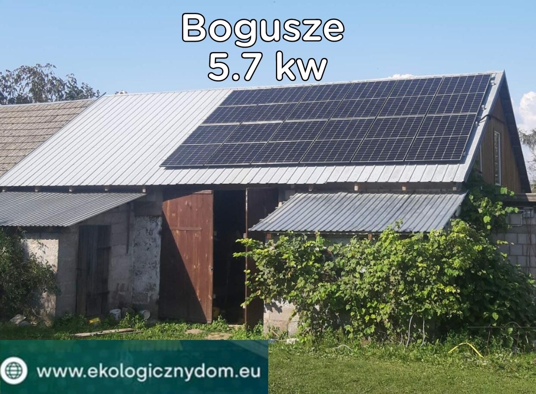 Instalacja paneli słonecznych o mocy 5.7 kW na dachu budynku gospodarczego z blachy trapezowej, widok z poziomu gruntu, częściowo zasłonięte przez roślinność.