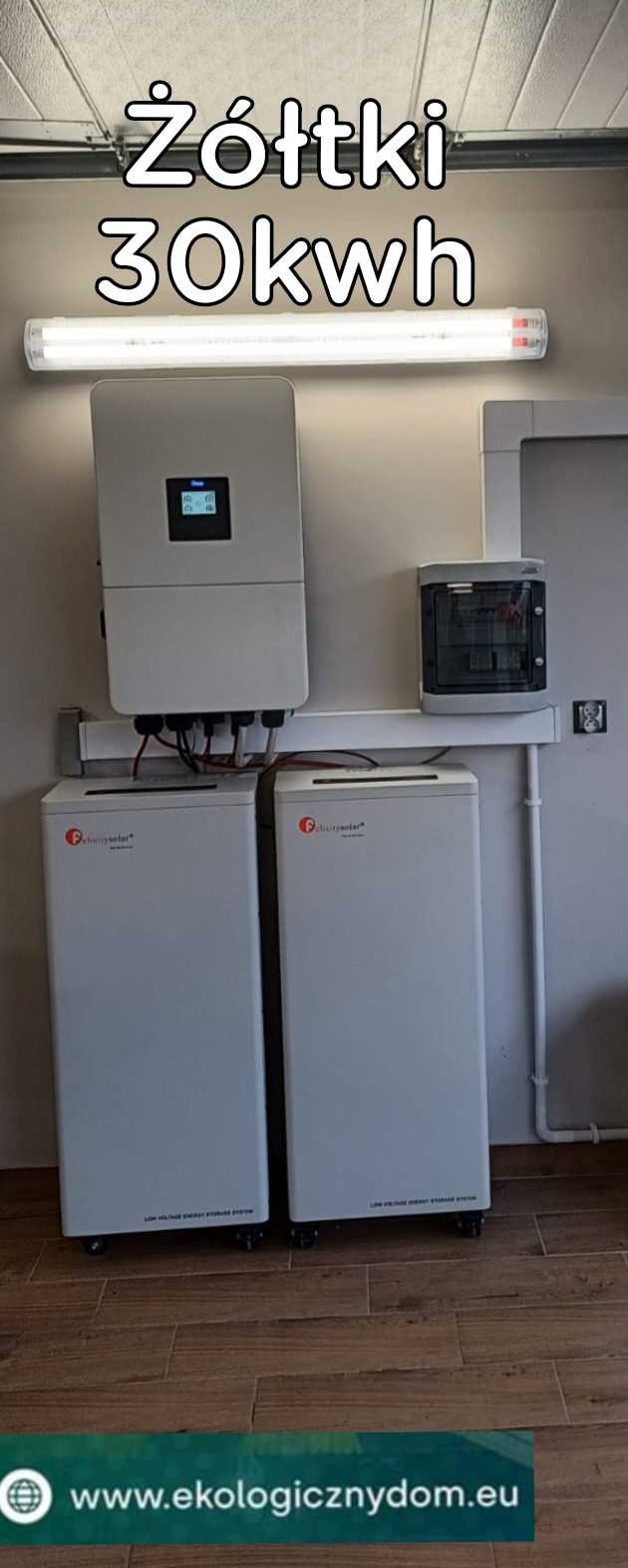 Dwa białe magazyny energii Felicitysolar z falownikiem na ścianie w pomieszczeniu. Widoczna skrzynka elektryczna i oświetlenie. Na dole adres strony internetowej.