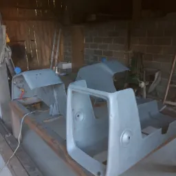 Elementy karoserii pojazdu po obróbce, przygotowane do dalszych prac, leżące na stole w warsztacie z ceglaną ścianą w tle.