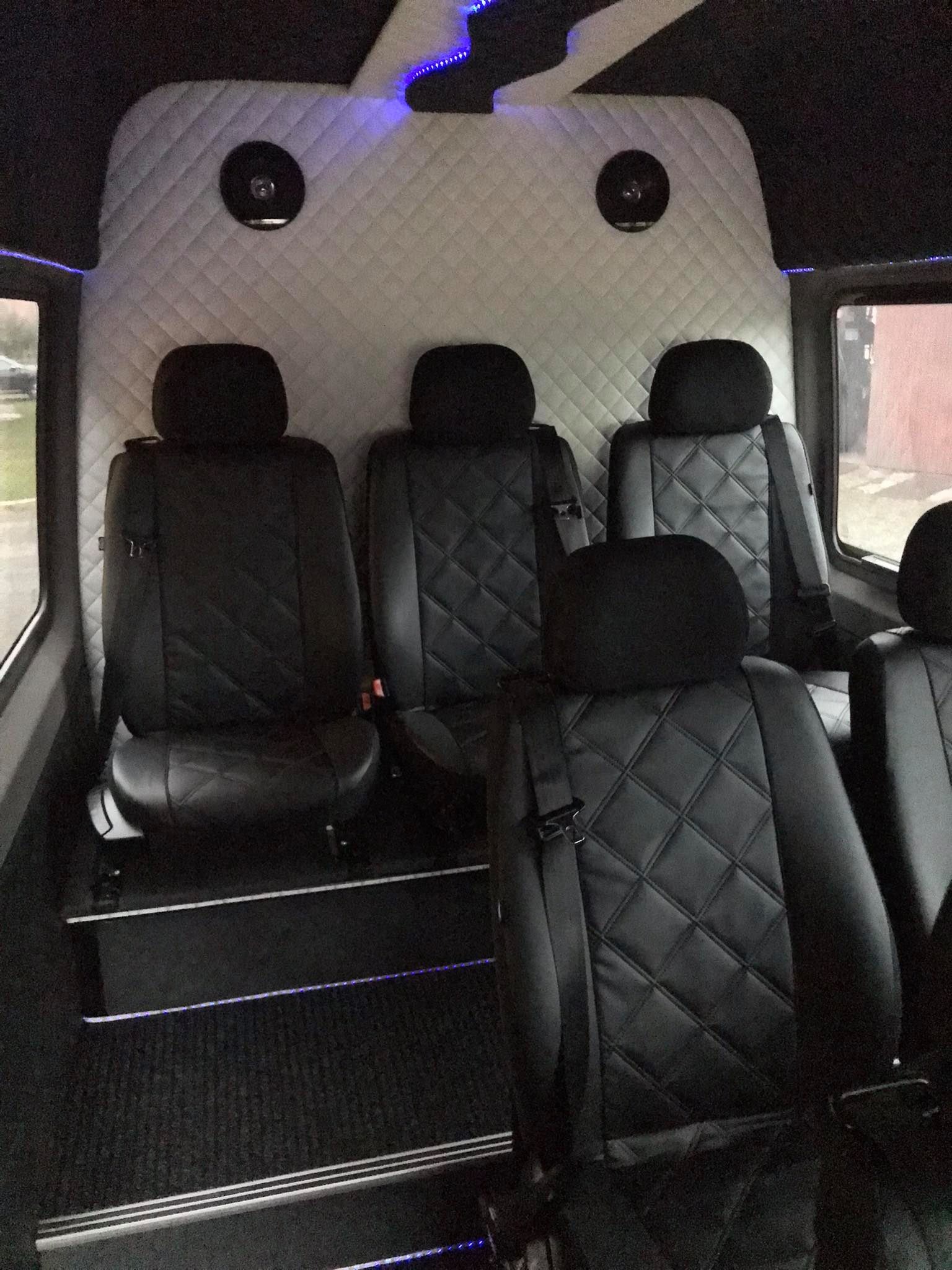 Wnętrze luksusowego busa z pikowanymi skórzanymi siedzeniami, oświetleniem LED i głośnikami w suficie.
