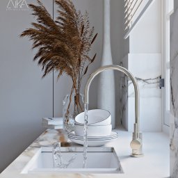 ATKA Architektura Wnętrz Agata Tokarz - Nowoczesna umywalka z marmurowym blatem, złotą armaturą i dekoracyjnym bukietem suszonych traw w szklanym wazonie, uzupełnona minimalistyczną ceramiką i wysoką, białą wazą w tle, oświetlona przez...