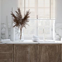 ATKA Architektura Wnętrz Agata Tokarz - Jasna kuchnia z drewnianymi szafkami, marmurowym blatem i backsplashiem, dekorowana wysokimi białymi wazonami, bukietem suszonych traw w szklanym wazonie, białymi miseczkami i czajnikiem.