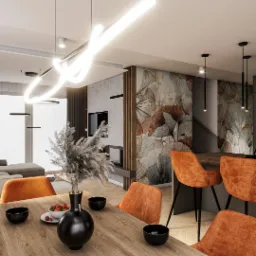 Stylowa jadalnia z drewnianym stołem, pomarańczowymi krzesłami i dekoracyjną ścianą w liście. Nad stołem oryginalna, neonowa lampa. Widok na salon z sofą.