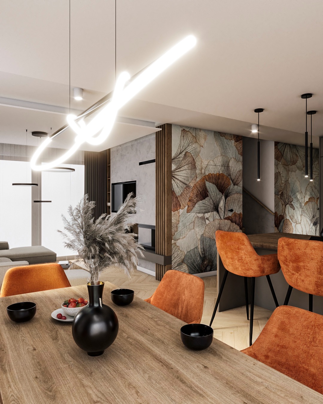 Stylowa jadalnia z drewnianym stołem, pomarańczowymi krzesłami i dekoracyjną ścianą w liście. Nad stołem oryginalna, neonowa lampa. Widok na salon z sofą.