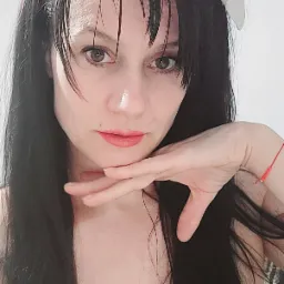 Portret kobiety z ciemnymi włosami, ozdobną opaską i delikatnym makijażem, opierającej brodę na dłoni.