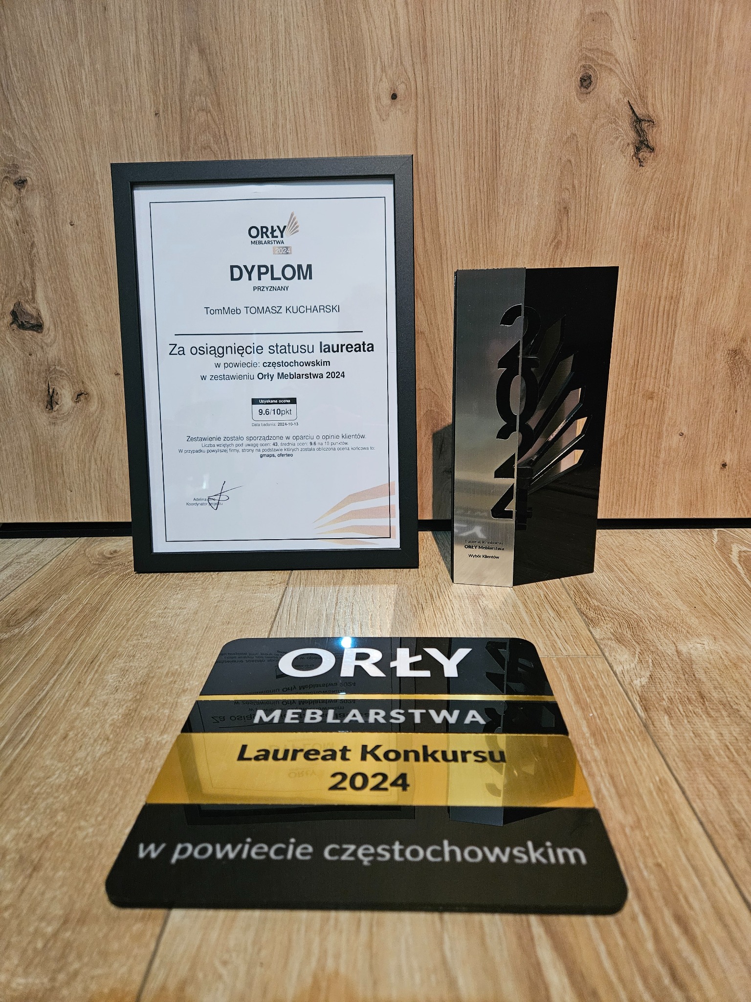 Dyplom i statuetka Orły Meblarstwa 2024 dla TomMeb Tomasz Kucharski za osiągnięcie statusu laureata w powiecie częstochowskim, na drewnianym tle.
