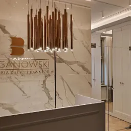 Recepcja w eleganckiej kancelarii radcy prawnego Barganowski, z marmurową ścianą, złotym logo i designerską lampą wiszącą.