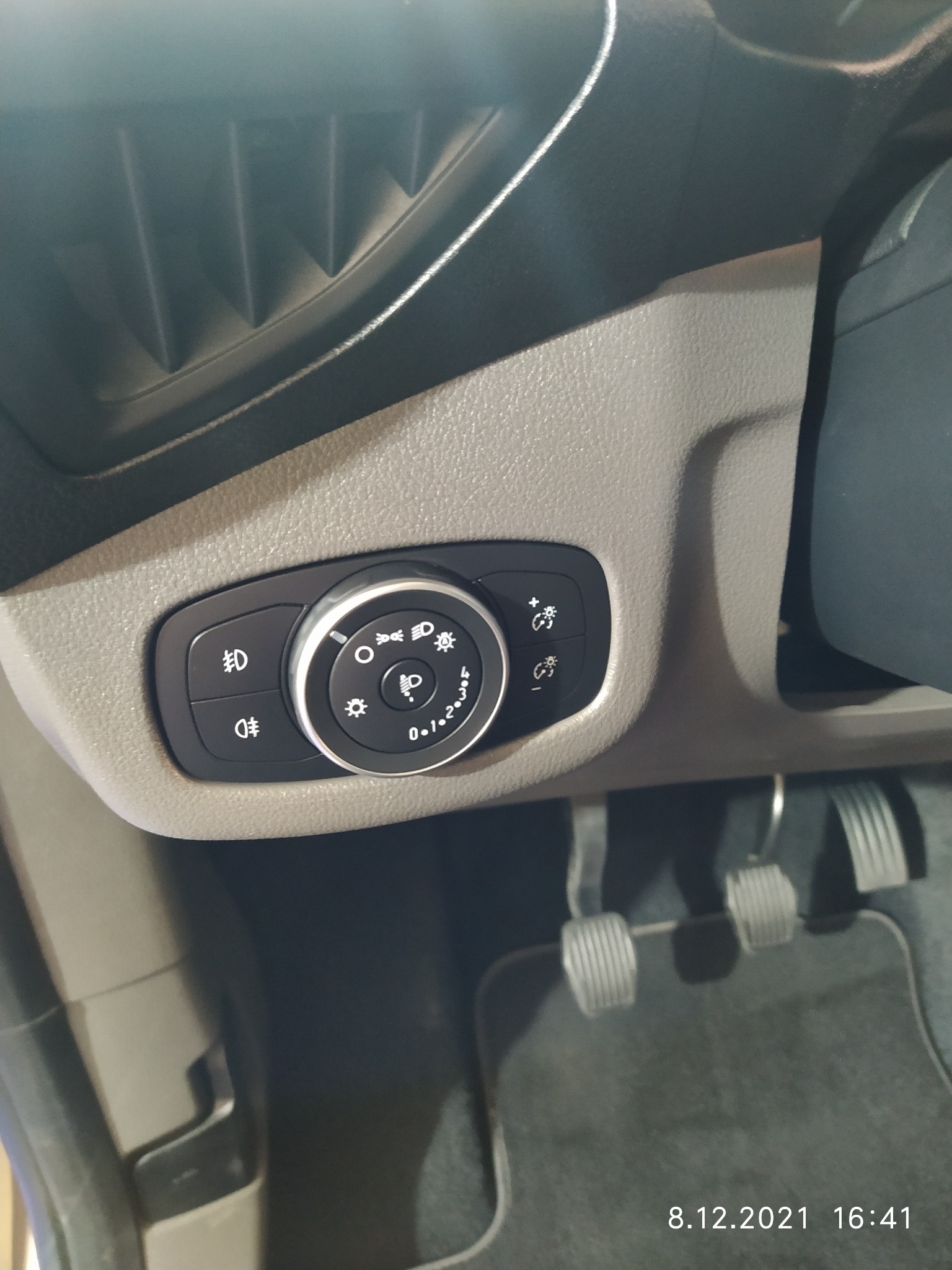 Panel sterowania oświetleniem w samochodzie Ford Transit, widoczne pedały i fragment dywanika.