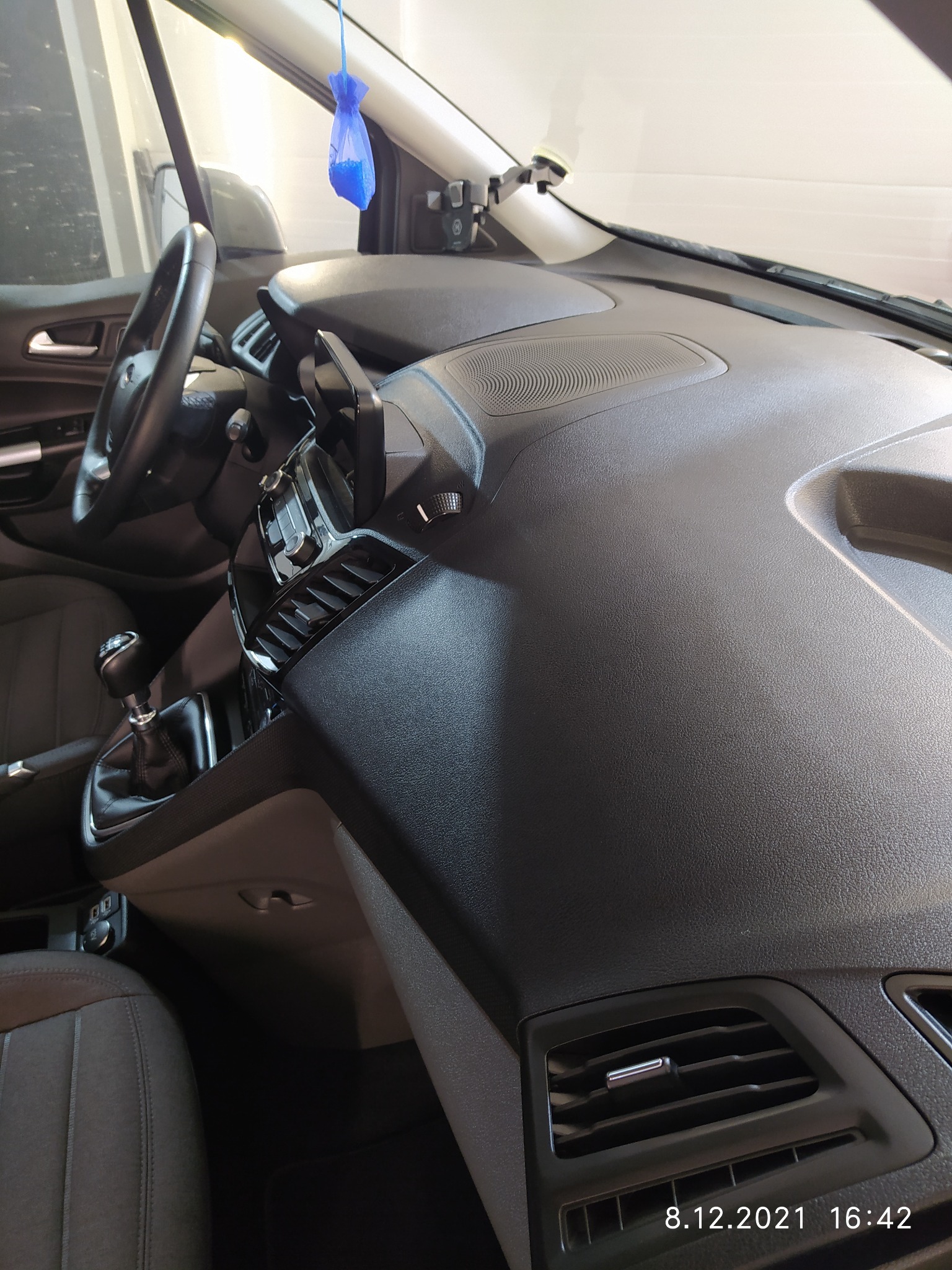 Wnętrze samochodu po czyszczeniu, widoczna deska rozdzielcza, kierownica i fragment fotela, z zawieszką zapachową.
