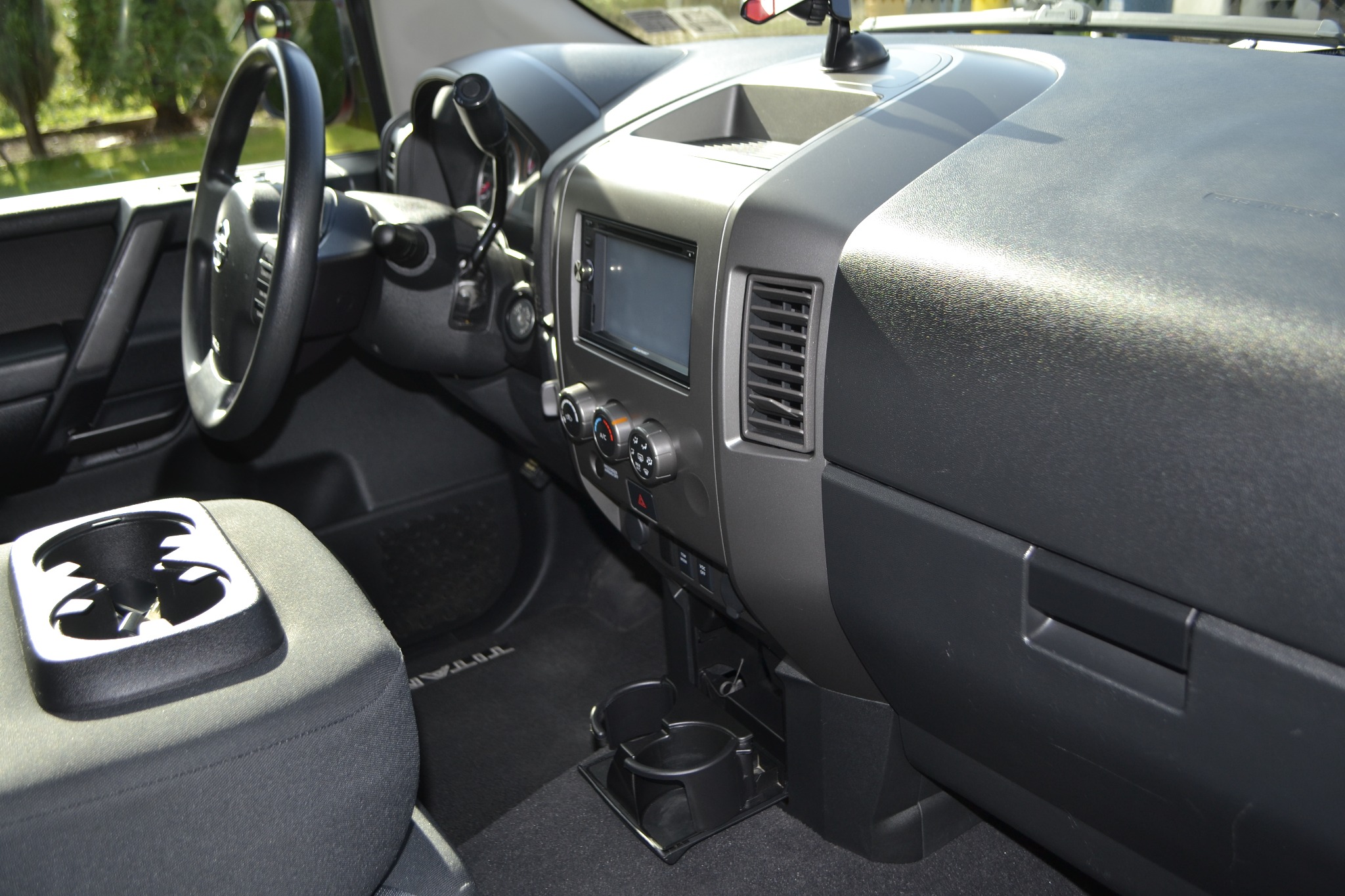 Wnętrze samochodu z widoczną deską rozdzielczą, kierownicą i uchwytami na napoje, w czystym i zadbanym stanie.