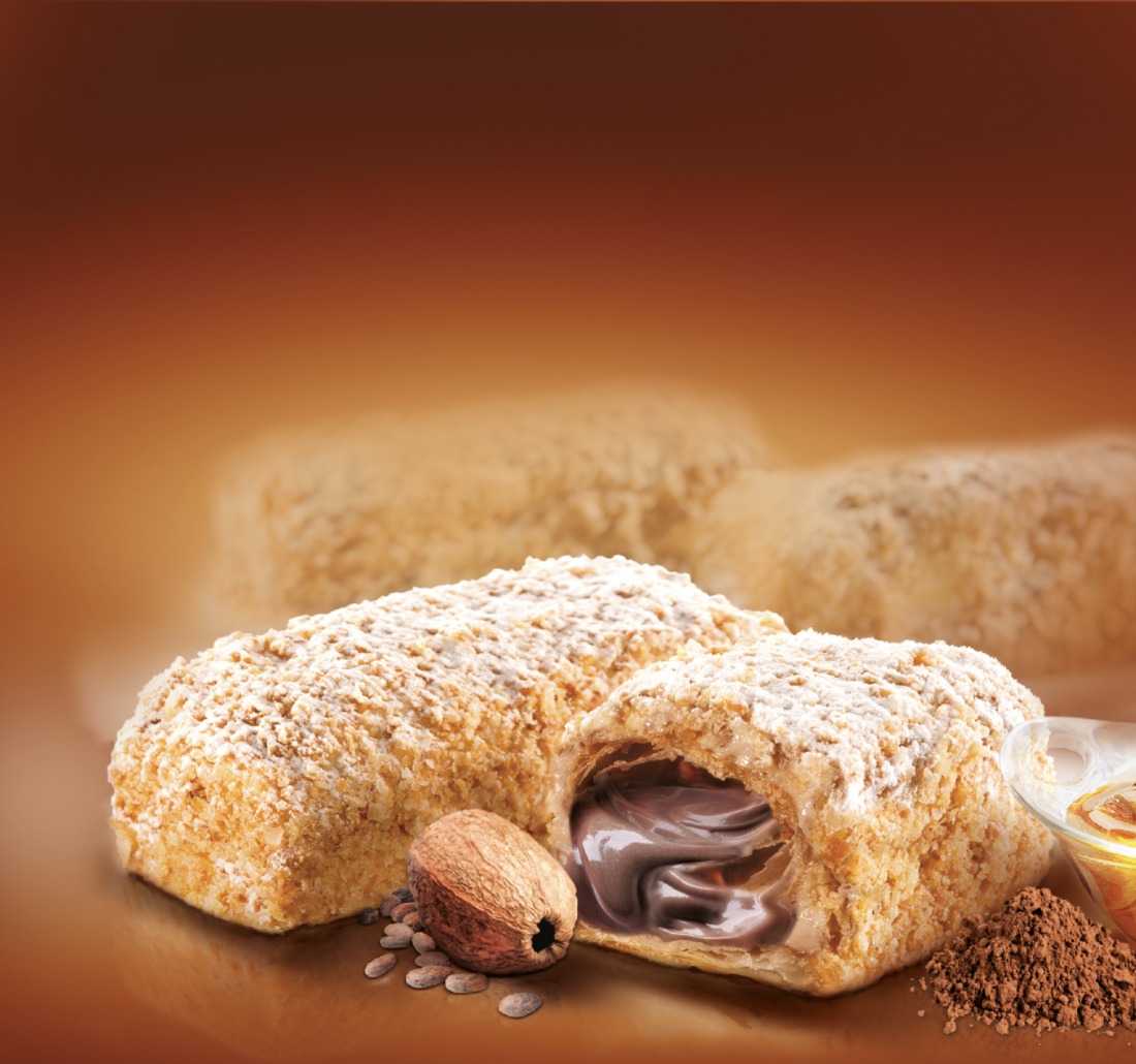 Dwa ciastka z kremem czekoladowym, posypane cukrem pudrem, z orzechem i kakao na błyszczącym brązowym tle.