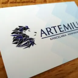 Wizytówka z logo kancelarii w formie geometrycznej głowy lwa w kolorach granatu i czerni, nazwa firmy 'ARTEMIUS KANCELARIA ADWOKACKA' zapisana ciemnogranatową czcionką.