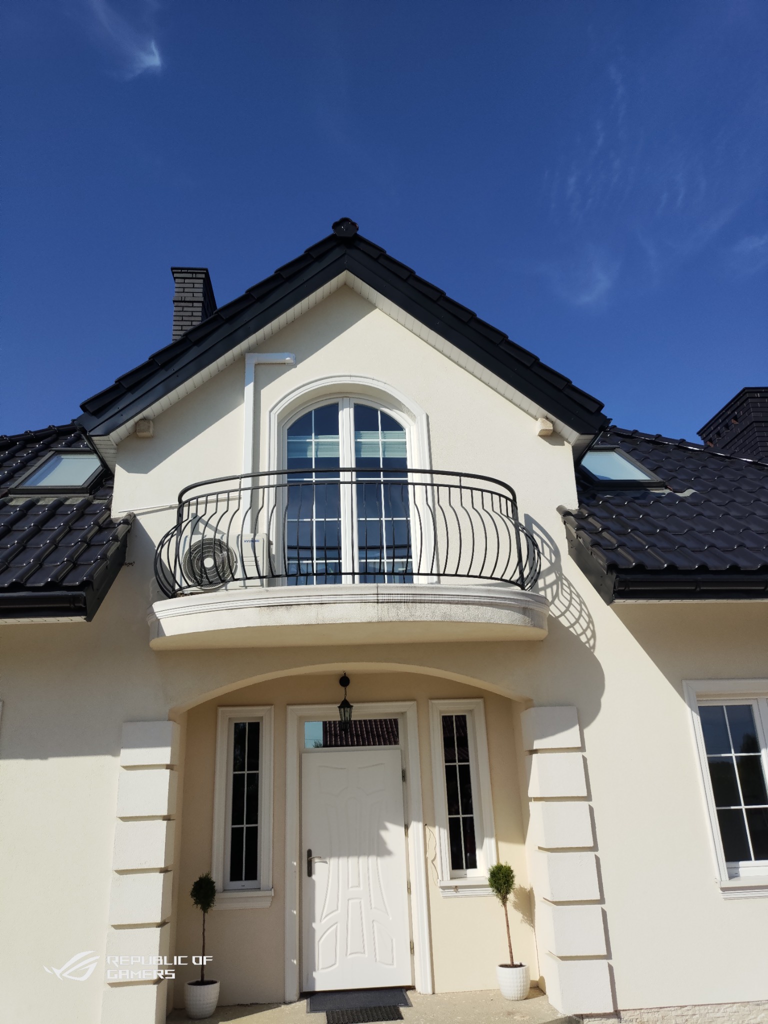 Elewacja domu jednorodzinnego z balkonem, na którym zamontowano zewnętrzną jednostkę klimatyzatora Hyundai.