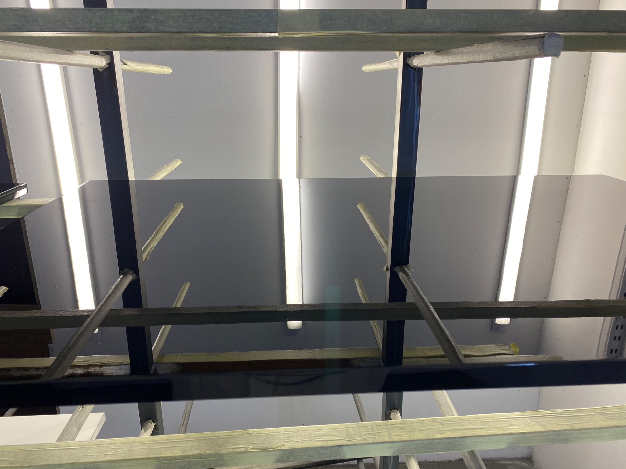 Szklany blat w trakcie produkcji, na drewnianych wspornikach w warsztacie pod oświetleniem LED.