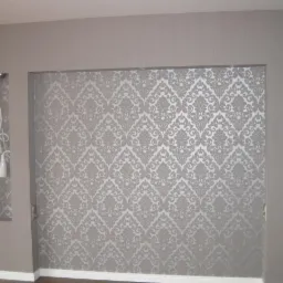 Wnętrze pokoju z tapetą w ornamenty i wnękami z oświetleniem. Dekoracyjne wykończenie ścian w odcieniach szarości.  Minimalistyczne lampy ścienne.