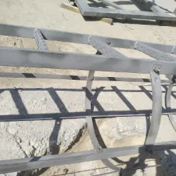 Metalowa konstrukcja pomalowana proszkowo na szaro, leżąca na betonowym podłożu. Widoczne detale łączeń i faktura farby.