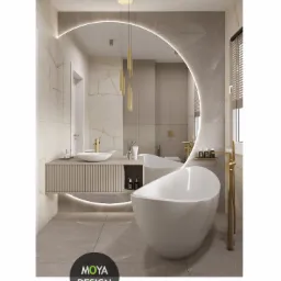 Elegancka łazienka z owalną wanną wolnostojącą, podświetlanym lustrem w kształcie łuku i złotymi akcentami, w tym armaturą i wiszącą lampą.