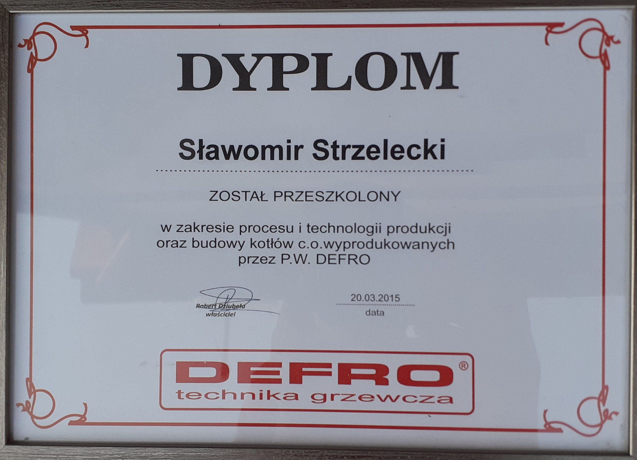 Oprawiony dyplom potwierdzający przeszkolenie Sławomira Strzeleckiego w zakresie procesu i technologii produkcji oraz budowy kotłów c.o. wyprodukowanych przez P.W. DEFRO, z datą 20.03.2015...