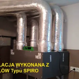 Zakończona instalacja rekuperacji z kanałami typu spiro, widoczne srebrne rury izolowane termicznie oraz centrala rekuperacyjna w piwnicy z oknem.