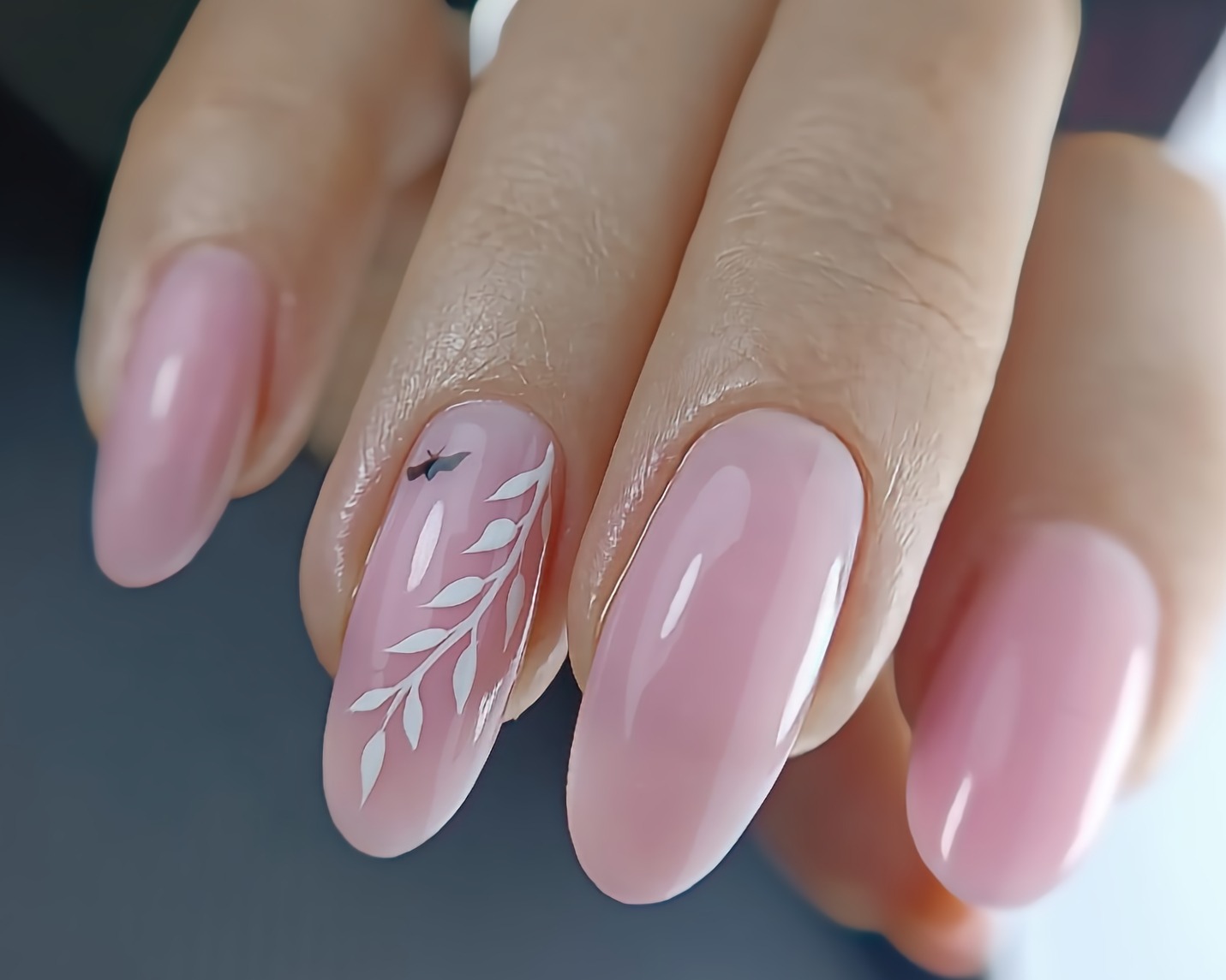 Delikatny manicure w odcieniach różu z motywem białych gałązek i czarnego ptaszka na jednym paznokciu, wykonany w Gdańsku.