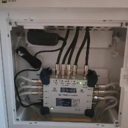 Multiswitch Telkom Telmor TT-5/8 FT w białej obudowie, widoczne podłączenia kabli koncentrycznych i zasilania, zielona dioda LED sygnalizuje działanie.