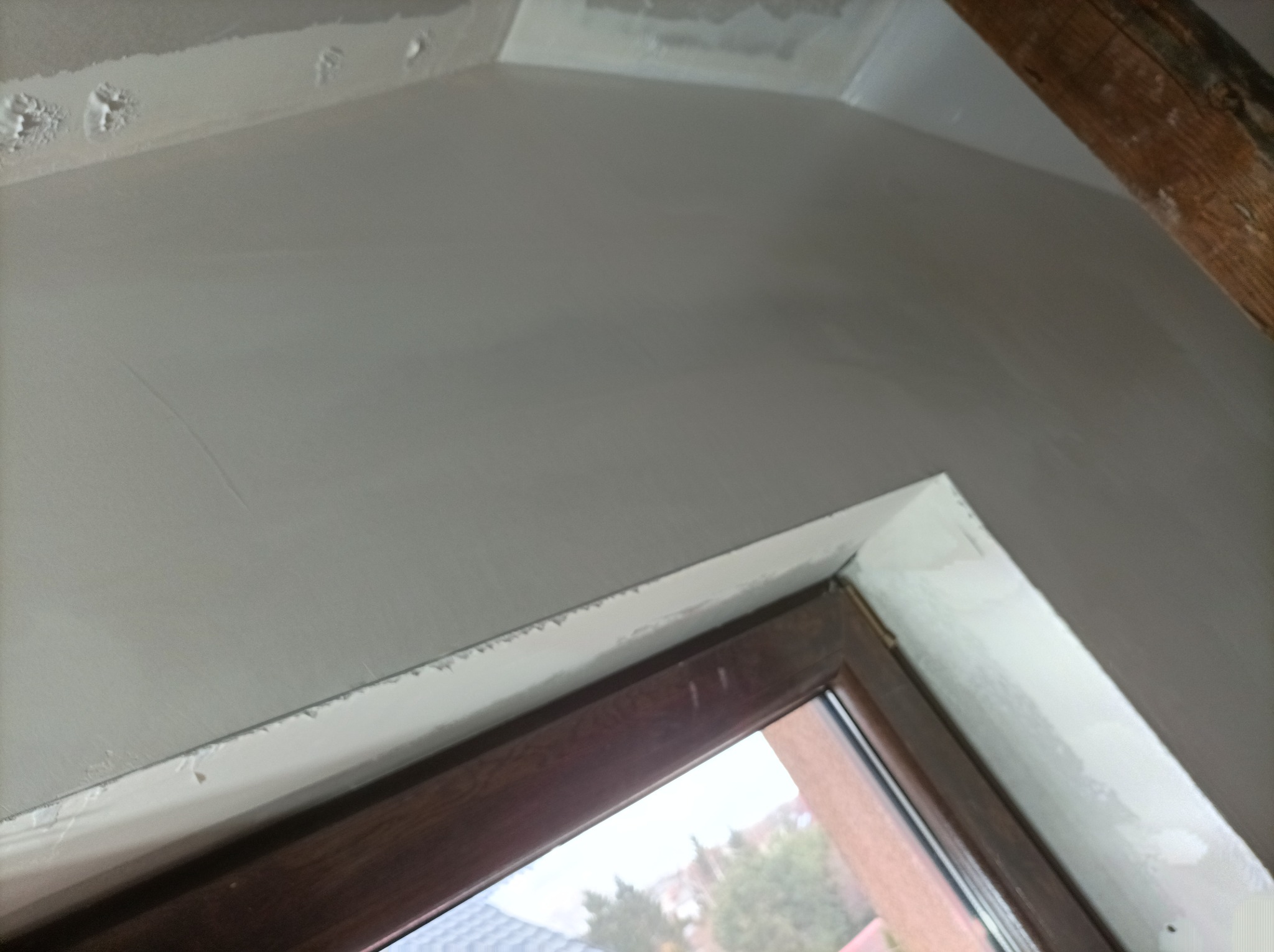 Ściana pod skosem po nałożeniu gładzi, widoczne niedoskonałości i nierówności w narożniku okna.