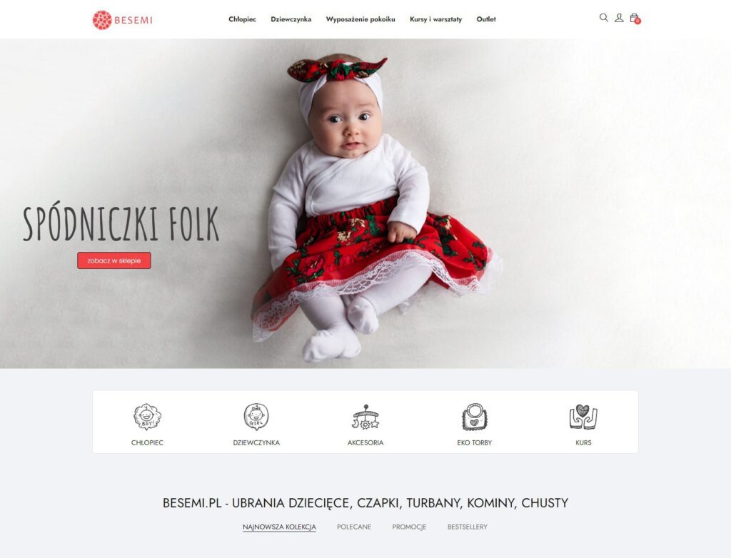 Strona internetowa sklepu Besemi.pl z ofertą spódniczek folk dla dziewczynek, prezentowana na zdjęciu niemowlę ubrane w białe body, czerwoną spódniczkę z folkowym wzorem i białą opaskę z kokardą.