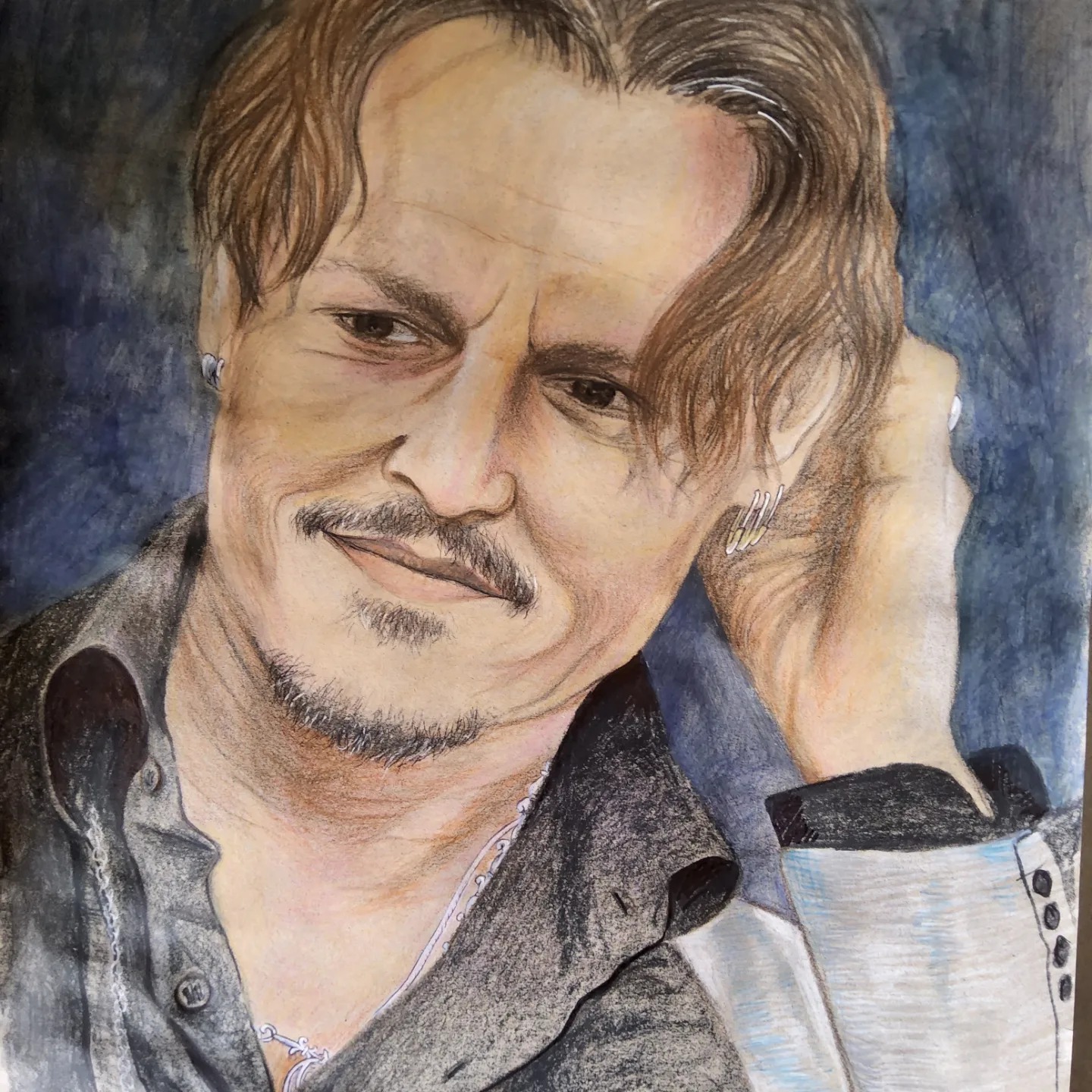 Portret mężczyzny z wąsami, wykonany kredkami ołówkowymi w odcieniach brązu, beżu i szarości, widoczne detale biżuterii w uszach i na szyi.