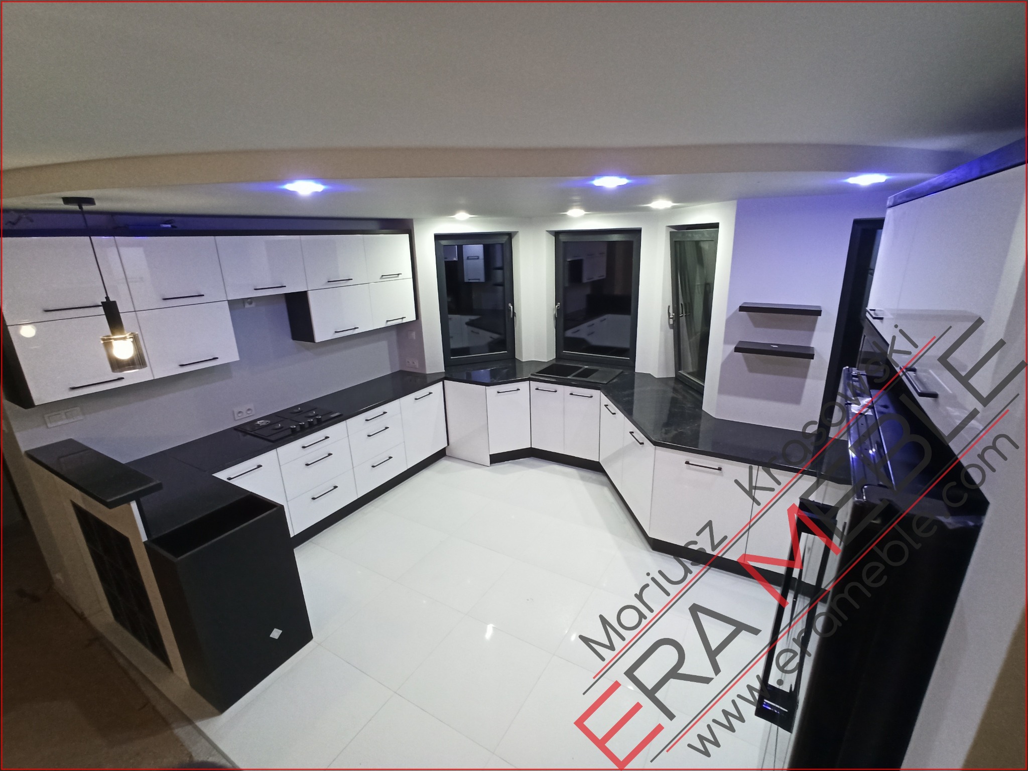 Nowoczesna, biało-czarna kuchnia w kształcie litery U z czarnym blatem, widziana z góry, z logo firmy na podłodze i oświetleniem LED pod szafkami.