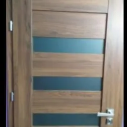 Drewniane drzwi wewnętrzne z poziomymi wstawkami z matowego szkła, widoczna klamka i zawiasy.