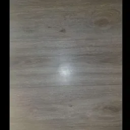 Pojedynczy panel podłogowy z wyraźnym rysunkiem słojów w odcieniach szarości, o matowym wykończeniu i widocznym delikatnym załamaniu światła.