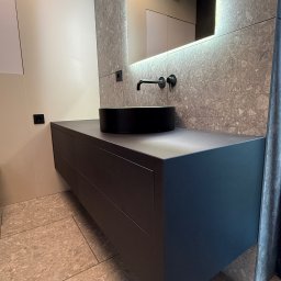 MSMeble (ZAKS) - Nowoczesna łazienka: ciemna szafka z umywalką typu misa, czarna armatura na tle ściany z płytek imitujących kamień i lustra z podświetleniem LED.