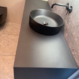 MSMeble (ZAKS) - Szara, okrągła umywalka nablatowa na blacie w łazience, z nowoczesną armaturą i płytkami imitującymi kamień. Minimalistyczny design.