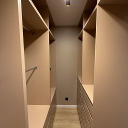 MSMeble (ZAKS) - Beżowa garderoba na wymiar z półkami, drążkami i szufladami, oświetlona punktowo, widok z perspektywy wnętrza, na podłodze panele.