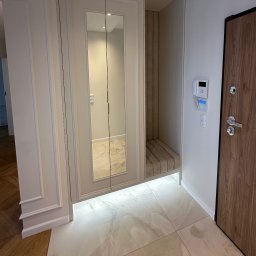 MSMeble (ZAKS) - Elegancka szafa wnękowa z lustrzanymi drzwiami i siedziskiem obok drewnianych drzwi wejściowych w jasnym przedpokoju. Nowoczesny design, marmurowe płytki na podłodze.