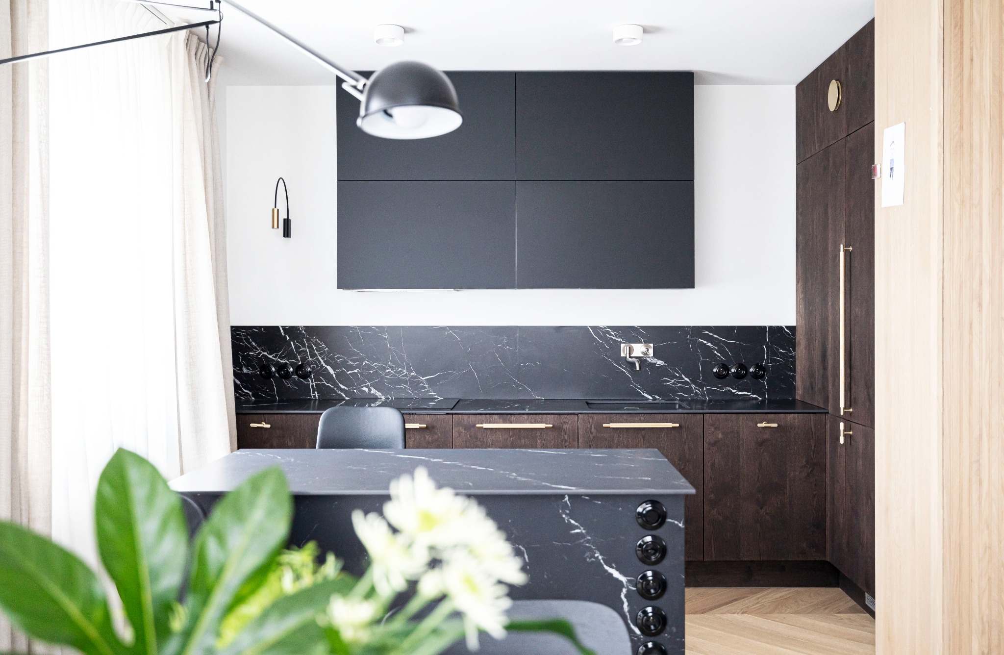 Nowoczesna kuchnia w Gorzowie Wielkopolskim z czarnymi marmurowymi blatami i backsplash, ciemnobrązowymi szafkami z poziomymi, złotymi uchwytami, czarnymi szafkami wiszącymi i wyspą kuchenną...