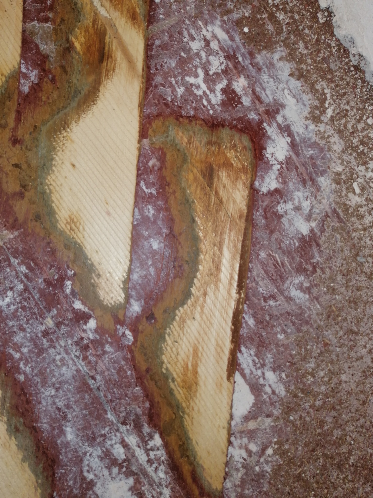 Fragment podłogi z częściowo usuniętą starą powłoką i śladami pyłu po szlifowaniu, ukazujący surowe drewno w miejscu obróbki.