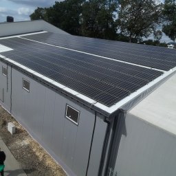 Solar - Ekspert s.c - Instalacja fotowoltaiczna na dachu budynku przemysłowego w Nasielsku, widok z góry, osoba przechodząca obok.