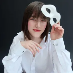 Portret kobiety w białej koszuli, trzymającej białą maskę karnawałową na tle ciemnego tła.