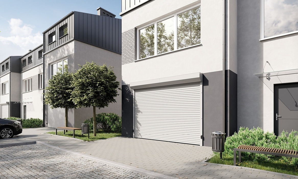 Nowoczesna brama garażowa rolowana, biała, zamontowana w budynku o minimalistycznej architekturze. Widoczne drzewa i elementy zagospodarowania terenu.